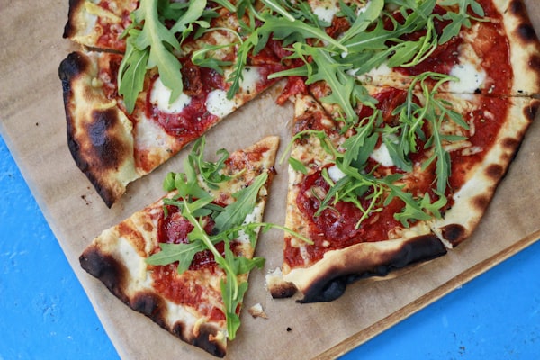 Arugula pizza on parchment with fresh greens