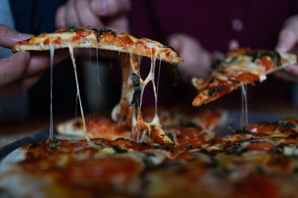 Sharing a pizza with friends — cheese pull family-style at Ganni's